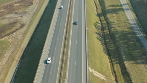 Aerial-view-of-cars-on-a-multi-lane-highway-with-shadows-of-trees