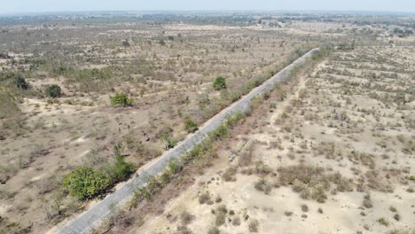 Aerial-shot-of-beautiful-vast-barren-land-near-Charu-village-in-Chatra,-Jharkhand,-India-with-a-road-passing-in-the-middle-and-a-bike-travelling