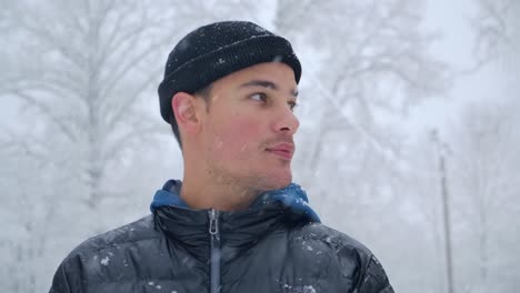 Attractive-Young-Man-Looking-at-Camera-and-Turning-Away-in-Snowfall-CU