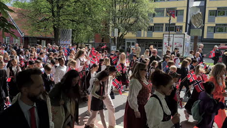 Niños-Y-Personas-Con-Trajes-Típicos-Caminando-Con-Banderas-En-Un-Desfile-Callejero-Durante-El-Día-De-La-Constitución,-Fiesta-Nacional-En-Oslo-Y-Noruega