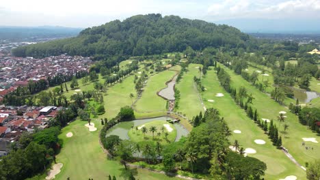 Vista-Aérea-Del-Campo-De-Golf-En-Medio-De-La-Ciudad-De-Magelang-Con-Una-Pequeña-Colina-Al-Fondo