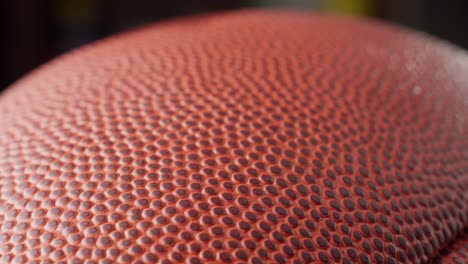 Rack-focus-extreme-close-up-of-red-brown-leather-of-American-football