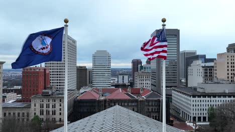 Banderas-De-Virginia-Y-Estados-Unidos-Ondeando-En-Lo-Alto-Del-Edificio-Del-Capitolio-En-El-Centro-De-Richmond,-Virginia