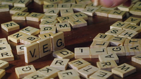 Person-Legt-Scrabble-Buchstaben-Auf-Die-Kante,-Um-Das-Wort-„vegan“-Auf-Dem-Tisch-Zu-Bilden