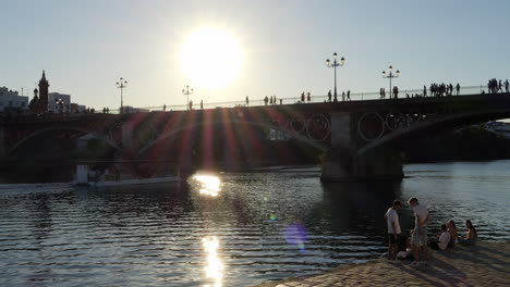 Sol-Brillante-Brillando-Sobre-El-Puente-De-Isabel-Ii,-Puente-De-Triana-Sobre-El-Río-Guadalquivir-En-Sevilla,-España