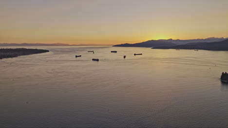 Vancouver-BC-Canada-Aerial-v63-drone-flyover-English-Bay-capturing-Burrard-inlet,-West-mountain-and-stunning-views-of-the-sun-sinking-below-the-horizon---Shot-with-Mavic-3-Pro-Cine---July-2023