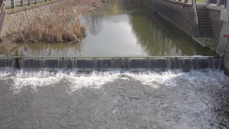 Ein-Fluss-Mit-Einem-Wehr,-Durch-Das-Wasser-Fließt