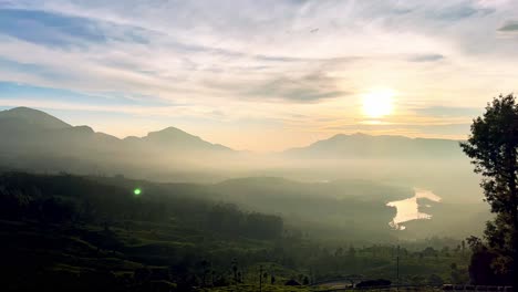 Vista-Aérea-De-Drones-En-Algún-Lugar-Hay-Una-Hora-Dorada-En-El-Cielo-Y-También-Se-Ve-Una-Gran-Montaña-Y-Hay-Muchas-Colinas-Y-árboles-Pequeños-Alrededor