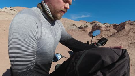 Un-Joven-Motociclista-Caucásico-Toma-Un-Descanso-En-Un-Viaje-En-Tierras-Baldías-Erosionadas