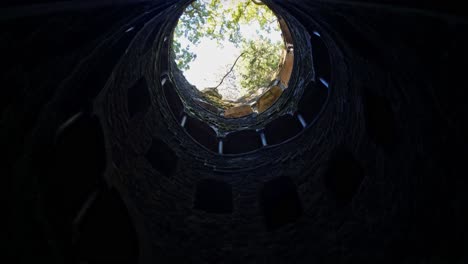 Low-angle-view-of-Quinta-da-Regaleira--well-shaft-with-spiral-staircase-during-daytime-in-Portugal