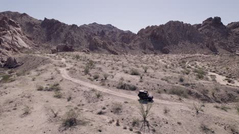 Drone-footage-of-a-black-Land-Rover-Defender-SUV-driving-through-a-desert-landscape