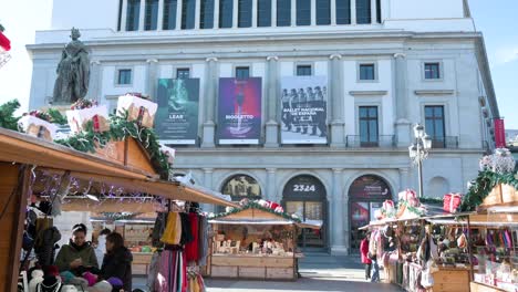 View-of-the-Teatro-Real-,-Spain's-foremost-institution-for-the-performing-and-musical-arts,-located-at-Plaza-Isabel-II-as-a-winter-Christmas-market-event-is-taking-place-in-front-of-it