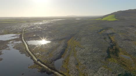 Panoramic-aerial-orbit-around-dramatic-flood-plains-in-the-Burren-Ireland-as-sunlight-glistens-on-water