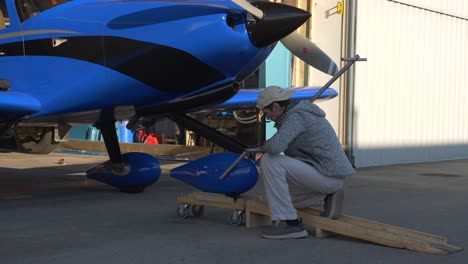 Pilot-Zieht-Flugzeug-Aus-Hangar-Mit-Schleppstange-Am-Bugfahrwerk-Befestigt