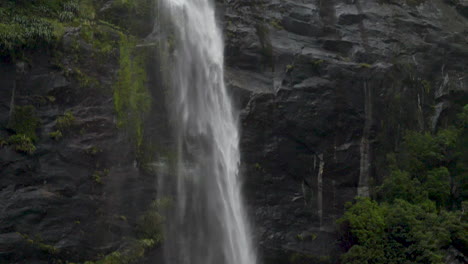 Panorámica-En-Cámara-Lenta-Por-Una-Pequeña-Cascada-En-Un-Acantilado---Milford-Sound,-Nueva-Zelanda