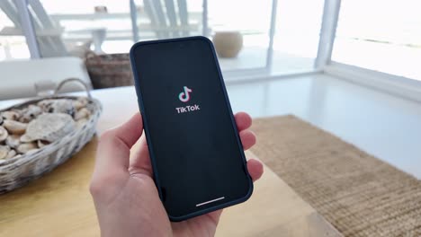 Opening-TikTok-App-on-Smartphone-with-Thumb-of-Caucasian-Hand-in-Slow-Motion