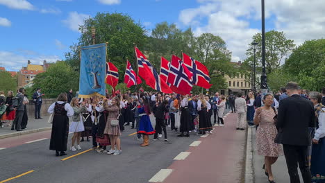 Street-Parade-in-Downtown-Oslo-During-Norwegian-Constitution-Day,-National-Flags-and-People-in-Folk-Costumes