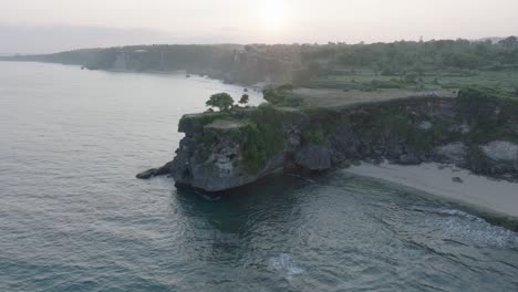 Aerial-drone-flying-over-tropical-Balangan-Beach-peninsula-at-sunrise-in-Uluwatu-Bali-Indonesia