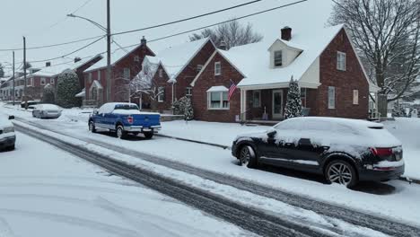 Snow-capped-parking-cars-at-street-in-front-of-row-of-houses-in-winter-snow