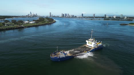 Sand-dredging-vessel-working-on-a-coastal-rejuvenation-project-with-an-urban-city-skyline-in-the-distance