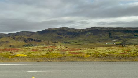 Mountains-on-countryside-in-Iceland,-POV-shot-from-side-of-driving-car