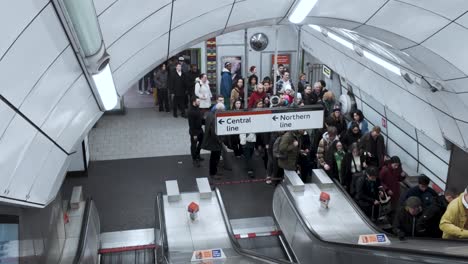 Bajando-Las-Escaleras-Mecánicas-En-La-Estación-De-Tottenham-Court-Road,-Mientras-Otros-Ascienden-En-El-Carril-Opuesto,-Lo-Que-Refleja-El-Ritmo-Bullicioso-De-Los-Desplazamientos-Diarios-Y-El-Transporte-Contemporáneo.