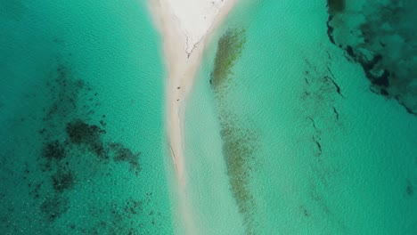 A-narrow-sandy-path-dividing-turquoise-waters,-aerial-view