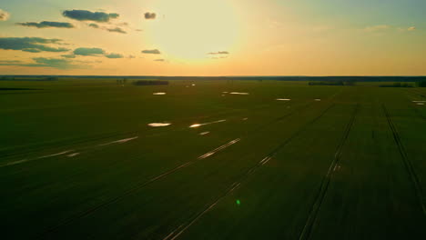 Goldener-Sonnenuntergang-über-Ackerlandfeldern-Mit-Dem-Himmel,-Der-Sich-Im-Bewässerungswasser-Spiegelt---Luftaufnahme