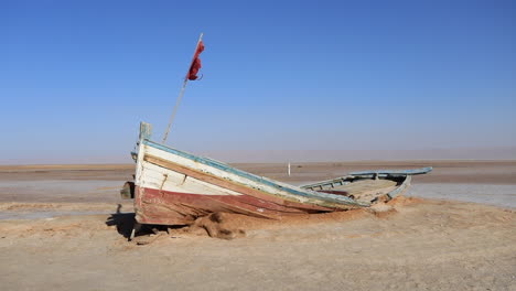 Abandoned-boat-on-the-salt-flats-of-Chott-el-Jerid,-Tunisia-under-a-clear-blue-sky