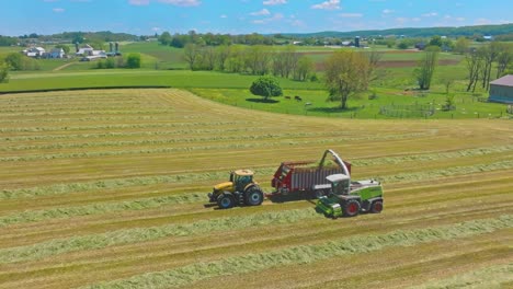 A-CLAAS-Tractors-work-in-harmony,-baling-hay-as-the-day-wanes,-transforming-fields-into-neatly-organized-lines,-under-azure-skies