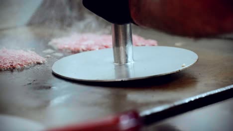4K-Cinematic-food-cooking-footage-of-a-chef-preparing-and-making-a-delicious-homemade-burger-in-a-restaurant-kitchen-in-slow-motion-smashing-the-beef-into-smashed-burgers-on-the-grill