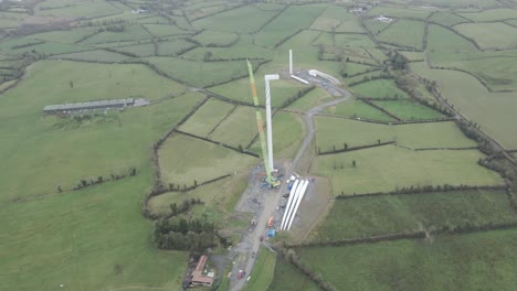 Aerial-shot-of-wind-turbine-construction-in-rural-Monaghan,-Ireland,-with-lush-green-fields