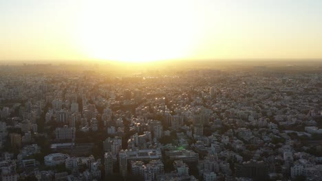 Aerial-drone-view-in-golden-hour-where-there-are-many-high-rise-buildings-and-low-rise-buildings-are-shining-and-residential-houses-are-also-visible-and-there-is-also-a-big-temple