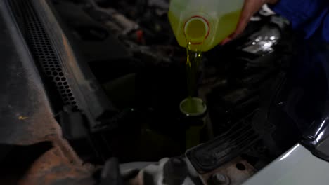 Detailed-shot-of-a-mechanic-pouring-windshield-cleaning-liquid-to-fill-the-tube-of-a-car,-4K