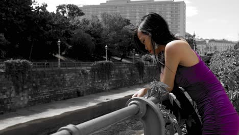 Thoughtful-young-woman-looking-down-over-handrail-in-purple-dress-in-Vienna,-Austria