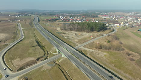 Aerial-view-of-cars-on-highway,-forest-and-farm-fields-during-sunny-day