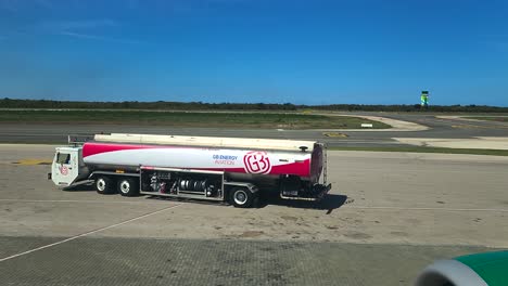 GB-Energy-Aviation-Tanklaster-Fährt-Vom-Internationalen-Flughafen-Punta-Cana-Weg,-Aus-Flugzeugfenster-Mit-Kontrollturm-Im-Hintergrund-Betrachtet