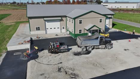 Workers-pave-new-parking-lot-beside-a-spacious-barn-on-a-crisp-autumn-day