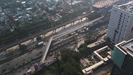 Aerial-shot-of-metro-train-track-near-highway-with-cars-and-buildings