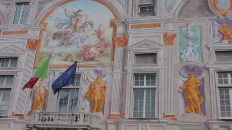 Panning-left-to-right-shot-of-ornate-murals-covering-exterior-of-Palazzo-San-Giorgio-in-Genoa,-Italy