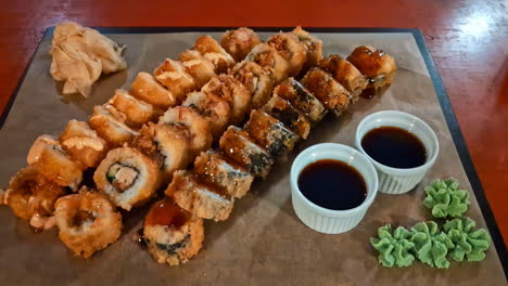 Descend-to-frieds-sushi-rolls-with-ginger-pile,-wasabi-flower,-and-soy-sauce-on-tray