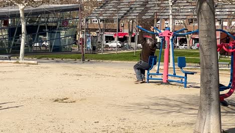 We-see-an-elderly-person-performing-an-exercise-routine-in-a-public-park-equipped-with-exercise-machines