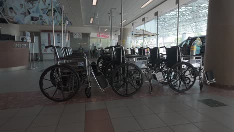 Hospital-in-an-Asian-country-taxi-and-car-drop-off-point-featuring-rows-of-wheelchairs-parked,-in-slow-motion-half-speed