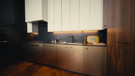 Toma-De-Una-Cocina-Moderna-En-Tonos-Oscuros-Con-Acabados-En-Blanco,-Dorado,-Negro-Y-Madera