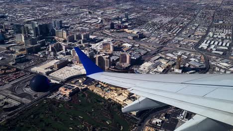 Wing-of-Airplane-Flying-Above-Las-Vegas-Strip,-Passenger-POV-of-Hotel-Casino-Resorts-and-City