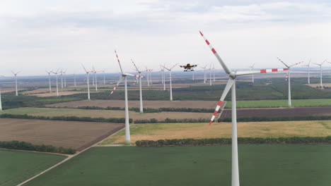 A-yellow-survey-maintenance-drone-approaches-a-wind-turbine-for-further-inspection-of-potential-damage