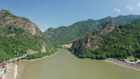 Aerial-shot-of-Olt-River-flowing-through-the-scenic-Cozia-Mountains,-lush-greenery-surrounding