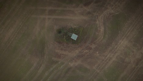 Drone-shot-of-a-deer-stand-in-the-middle-of-a-field-with-visible-tractor-trails
