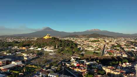 Aerial-view-rising-over-the-cityscape-of-San-Andres-Cholula,-golden-hour-in-Puebla,-Mexico