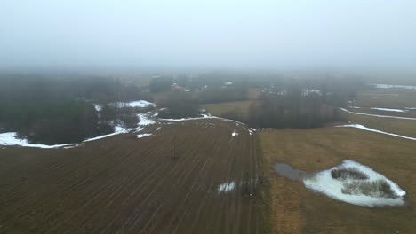 Paisaje-Rural-Brumoso-A-Principios-De-Primavera-Con-Parches-De-Nieve-Derritiéndose,-Vista-Aérea